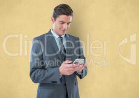 Businessman using smart phone against yellow background