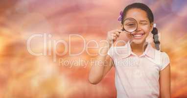 Happy girl looking through magnifying glass over bokeh