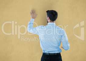 Rear view of businessman touching yellow background