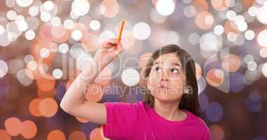 Curious girl looking up while holding pencil over bokeh