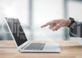 Hand pointing at laptop against blurry grey office with flare