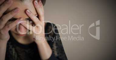 Woman hands over face against brown background