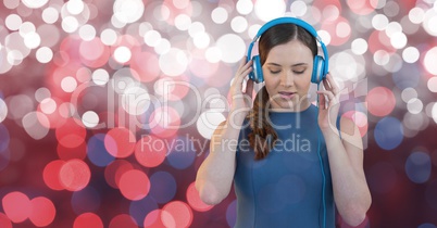 Young female hipster listening to music on headphones against bokeh