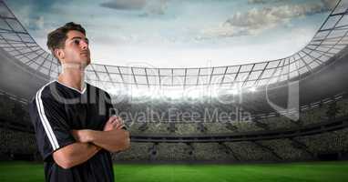 Soccer player with arms crossed looking away at stadium