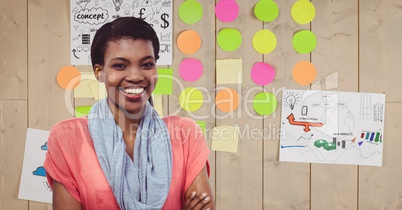 Smiling businesswoman with adhesive notes and papers stuck on wall