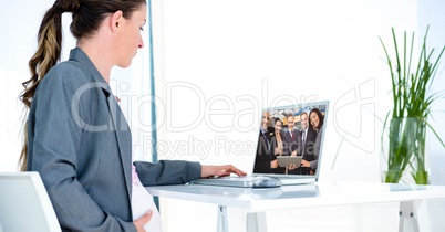 Pregnant businesswoman video conferencing with partners on laptop at office