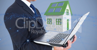 Midsection of businessman holding laptop against 3d house