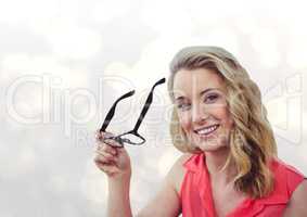 Portrait of smiling woman holding eyeglasses over bokeh