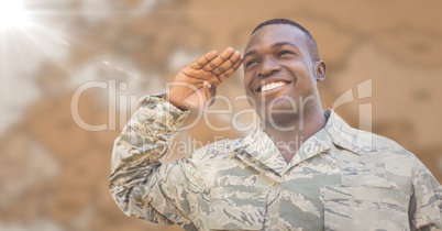 Soldier smiling and saluting against blurry brown map with flare