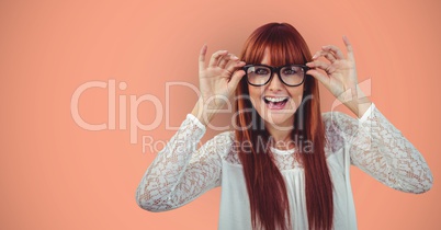 Cheerful redheaded female hipster wearing eyeglasses against orange background