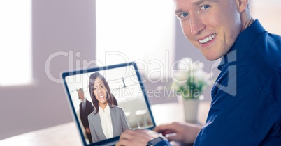 Smiling businessman video conferencing with colleague on laptop in office