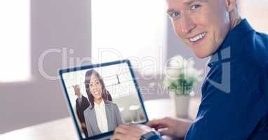 Smiling businessman video conferencing with colleague on laptop in office