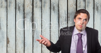 Portrait of confident businessman shrugging shoulders against wooden wall