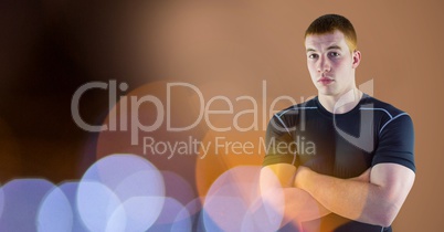 Fit young man with arms crossed by bokeh