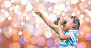 Little girl pointing while looking through binoculars over bokeh