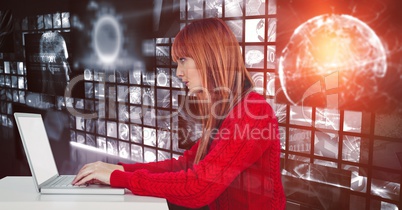 Female hacker using laptop against screens