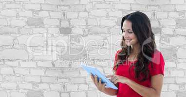 Smiling woman using tablet PC against wall