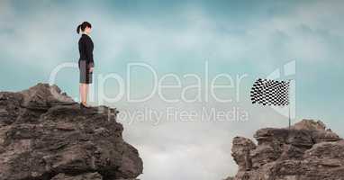 Young businesswoman and checker flag on rocky mountains against sky