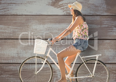 Side view of female riding cycle against wooden wall