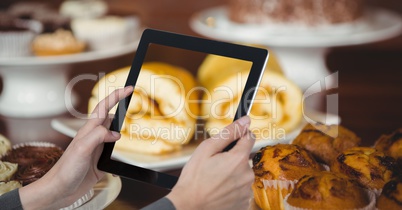 Hands taking picture of sweet food with tablet PC in coffee shop