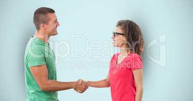 Side view of man and woman shaking hands over blue background