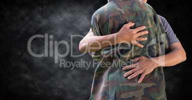 Soldier hugging mid section against black grunge background