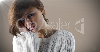 Woman sad face and head in hand against brown background with flare