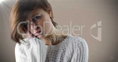Woman sad face and head in hand against brown background with flare