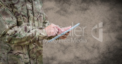 Soldier mid section with tablet and grunge overlay against brown background