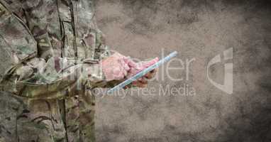 Soldier mid section with tablet and grunge overlay against brown background