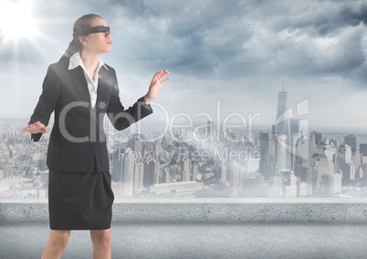 Business woman blindfolded with flare against skyline and grey clouds