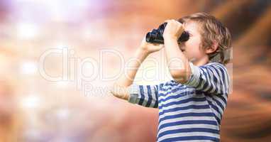 Boy looking through binoculars against blur background