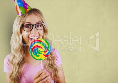 Happy woman wearing party hat while having lollipop