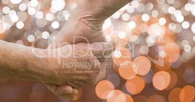Close-up of senior couple holding hands over bokeh