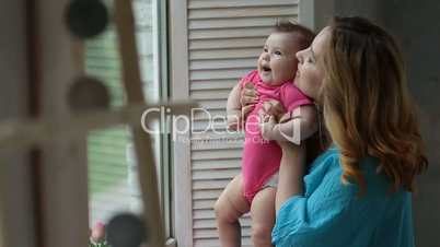 Happy mother with baby girl looking through window