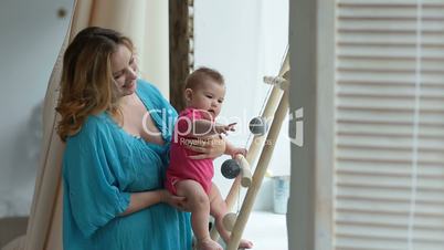 Cheerful mother checking baby's grasping reflex
