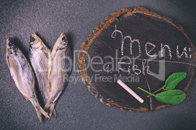 Three dried fish on a black surface