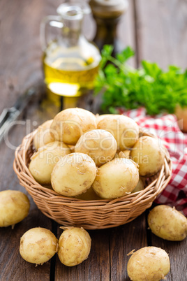 Raw potato in basket on wooden table closeup