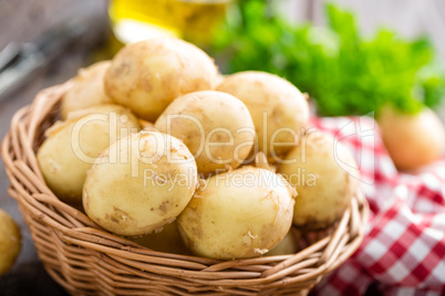 Raw potato in basket on wooden table closeup