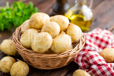 Raw potato in basket on wooden table closeup