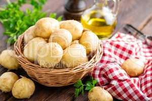 Raw potato in basket on wooden table closeup
