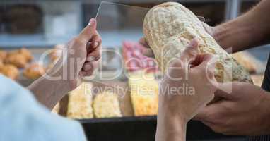 Hands photographing bread through transparent device