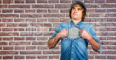 Hipster tearing shirt against brick wall