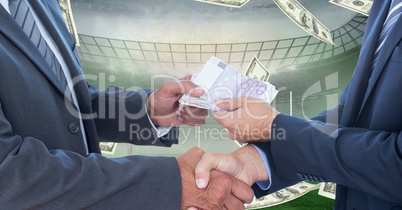 Business people exchanging money at football stadium representing corruption