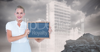 Businesswoman holding blank slate against building