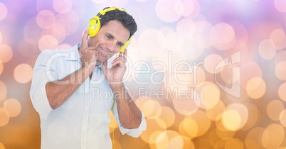 Smiling businessman listening to songs on headphones against bokeh