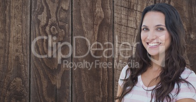 Young woman smiling against wooden wall