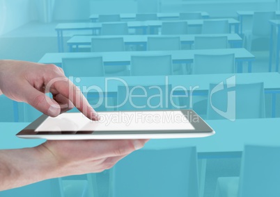 Hand touching a tablet in a blue classroom