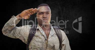 Soldier with backpack saluting against black grunge background