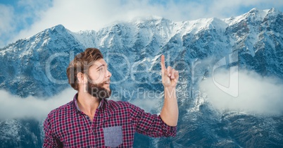 Male hipster pointing against snow covered mountains